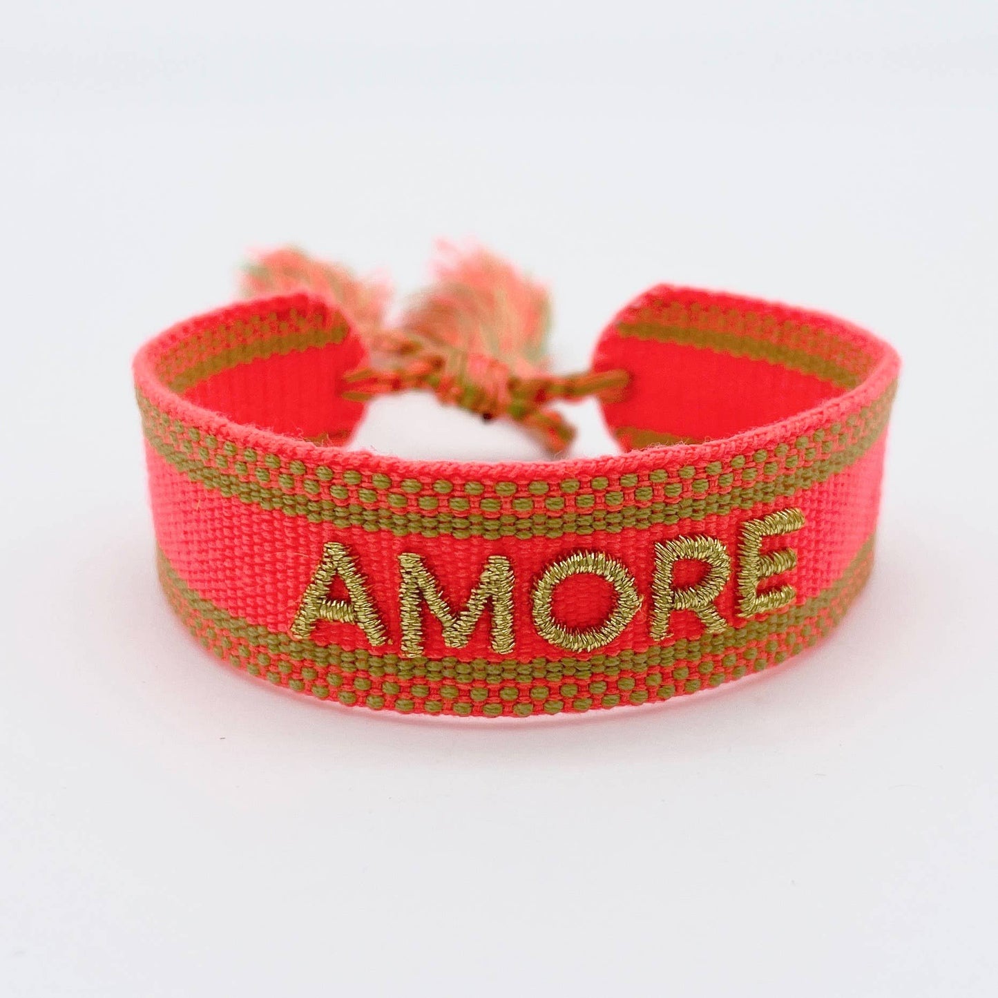 Gewebtes Armband in orange mit goldener Aufschrift "Amore" auf weißem Untergrund mit Quasten