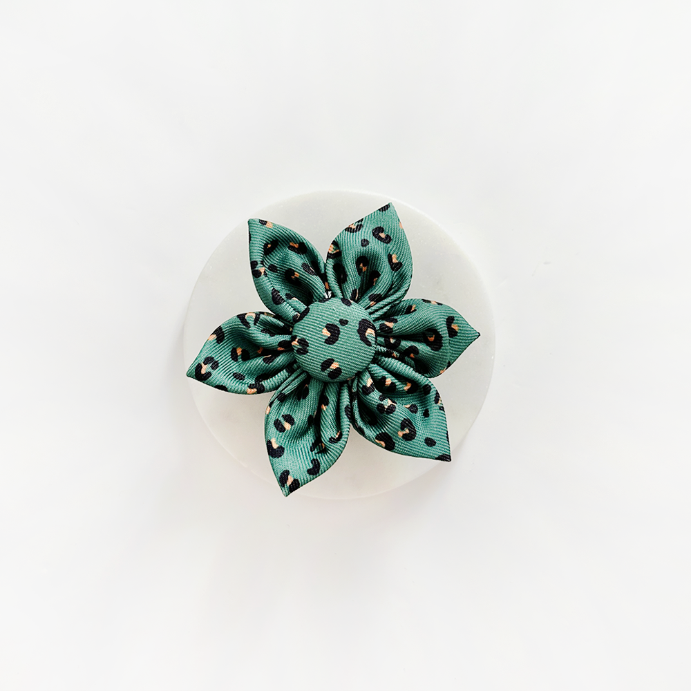 Blume aus Stoff gearbeitet, mit Leopardenmuster. Farben sind grün, schwarz und orange.