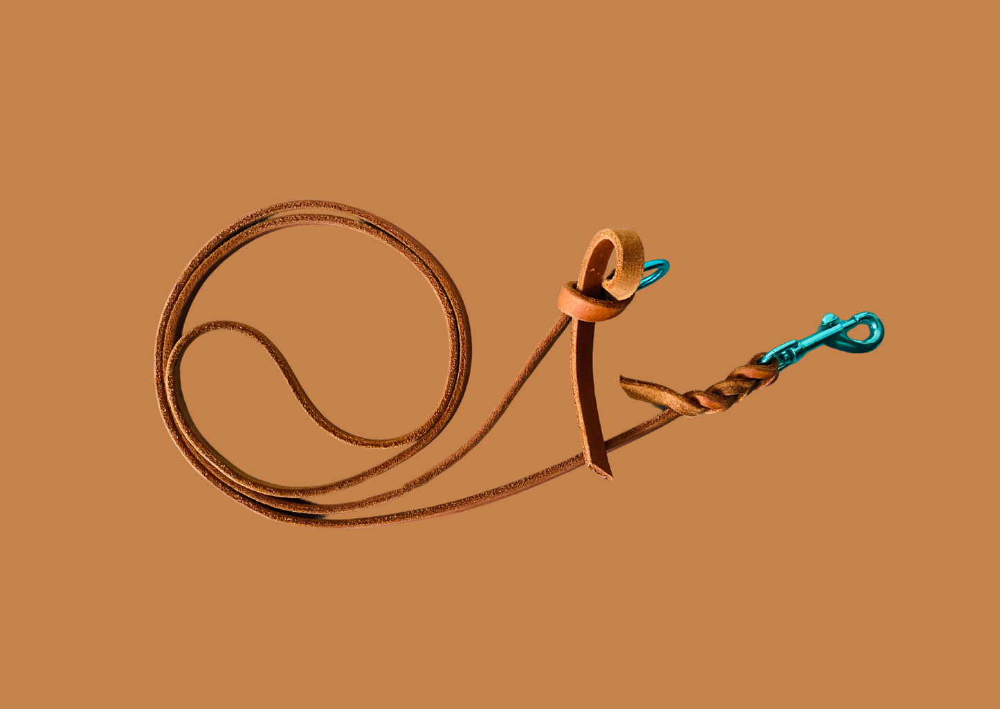 Hundeleine aus Leder in Cognac mit Karabiner und Ring in Türkis. Die Leine ist geflochten und hat am anderen Ende einen Knoten, der den Ring hält.
