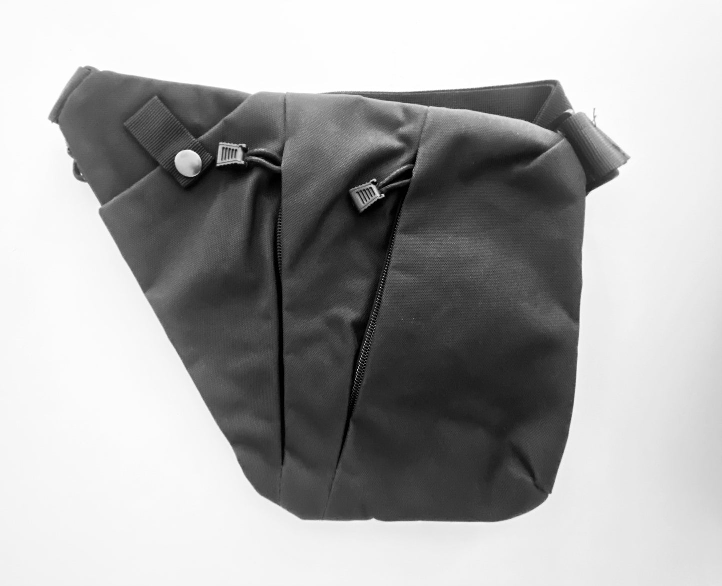 Tasche aus Canvas Stoff in schwarz. Die Tasche hat zwei Reißverschlüsse und ein Fach, das mit einem Koopf verschlossen ist.