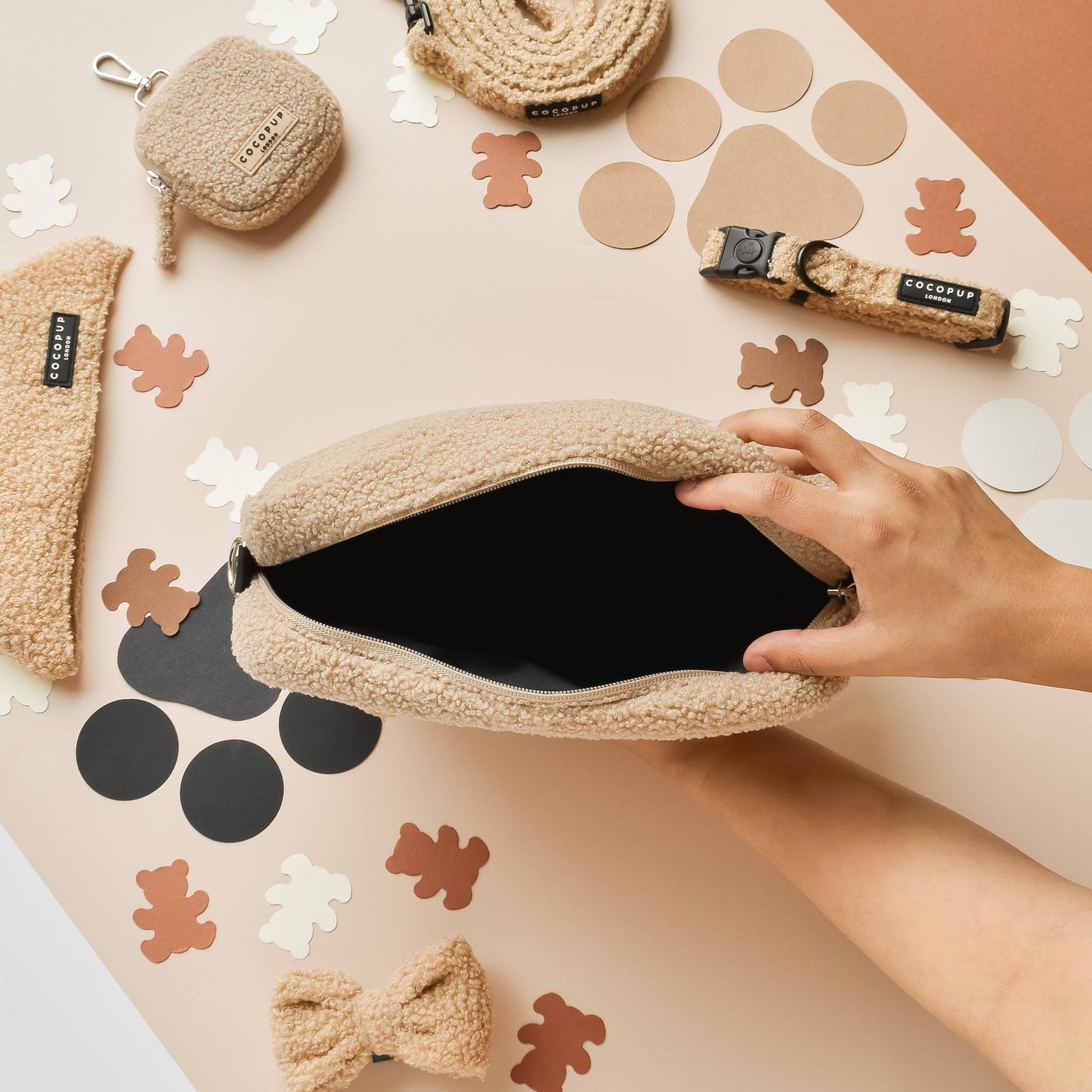 Geöffnete Tasche aus Teddystoff. Die Tasche wird von einer Hand aufgehalten. Im Hintergrund sind Halstuch, kleine Tasche, Halsband und Leine aus dem gleichen Material zu sehen.