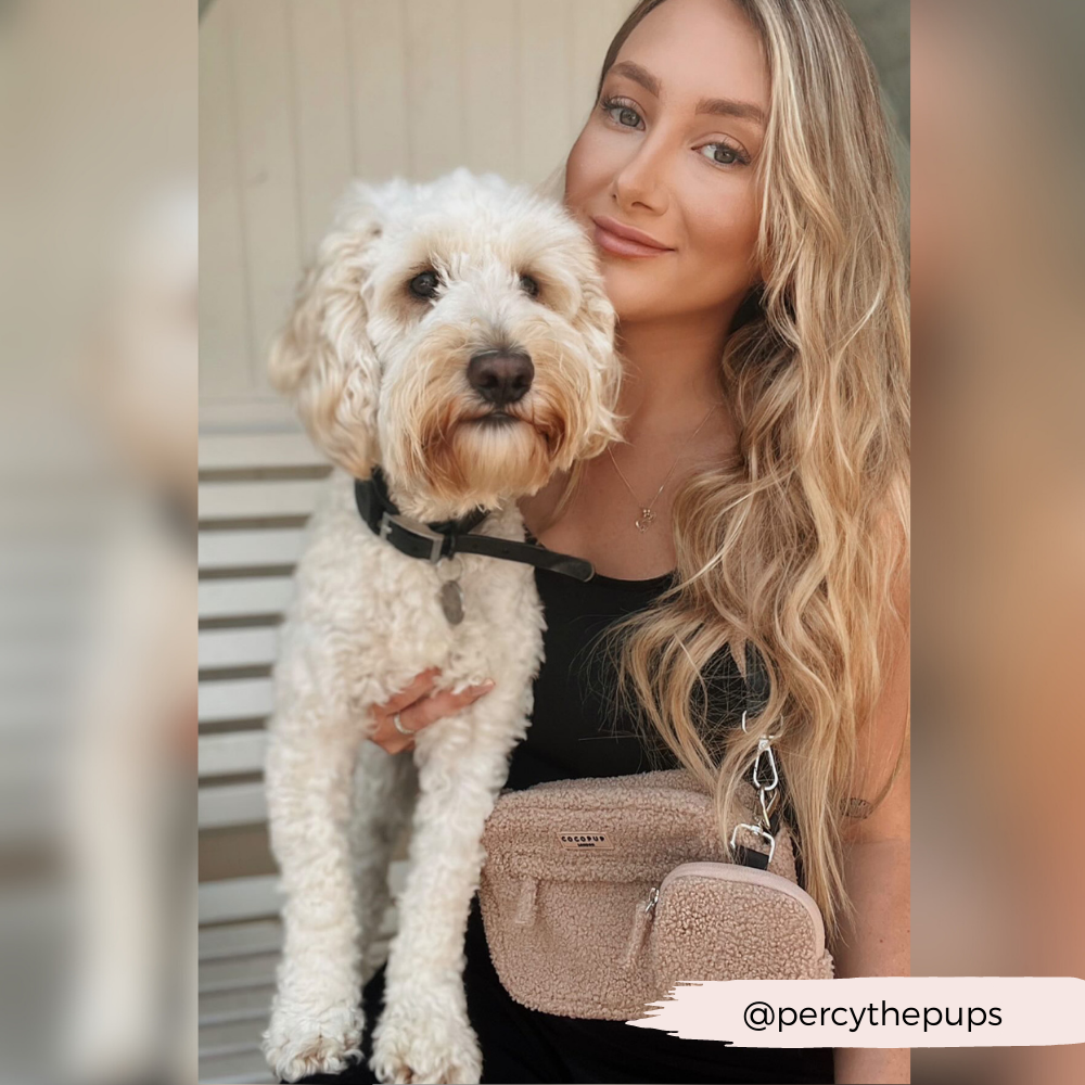 Blonde langhaarige Frau mit hellem Hund und beiger Tasche aus Teddystoff.