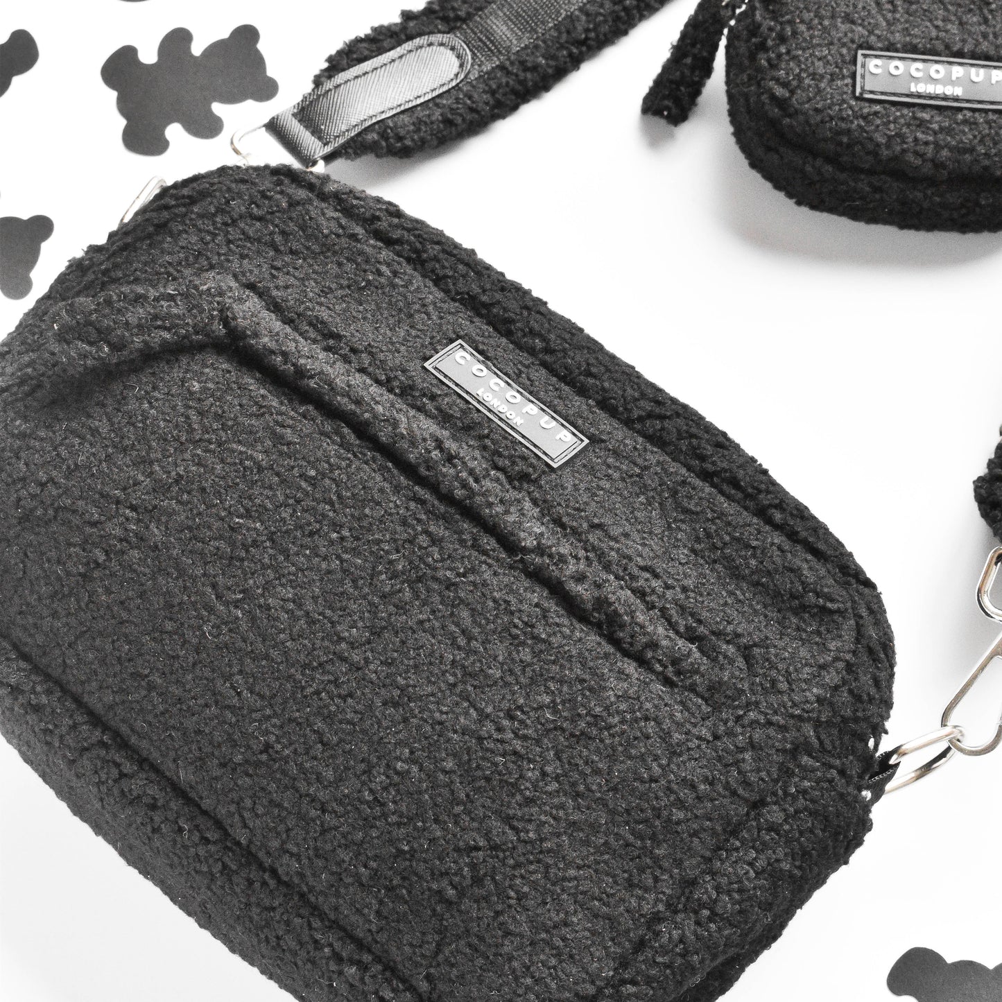 Tasche mit Träger und Reißverschluß. Das Material ist schwarz und ist Teddystoff. Die Teasche ist von seitlich unten fotografiert.