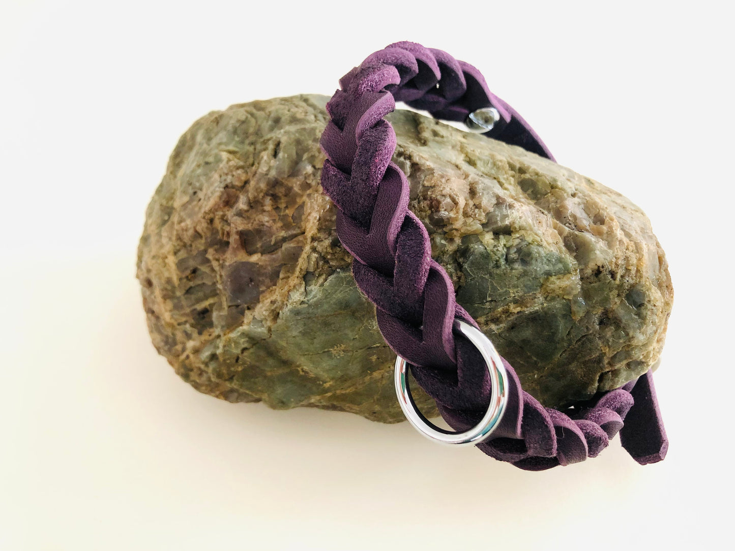 Hundehalsband aus LEder in ila mit Beschlägen in Silber liegt auf einem Stein.