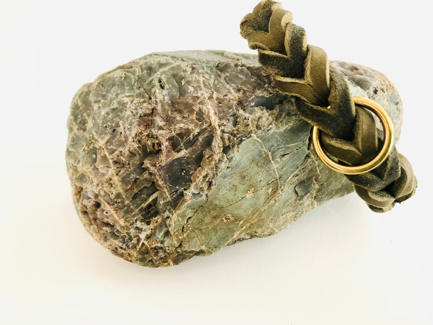 Halsband in Olive aus Leder geflochten mit goldenen Beschlägen an einen Stein gelehnt