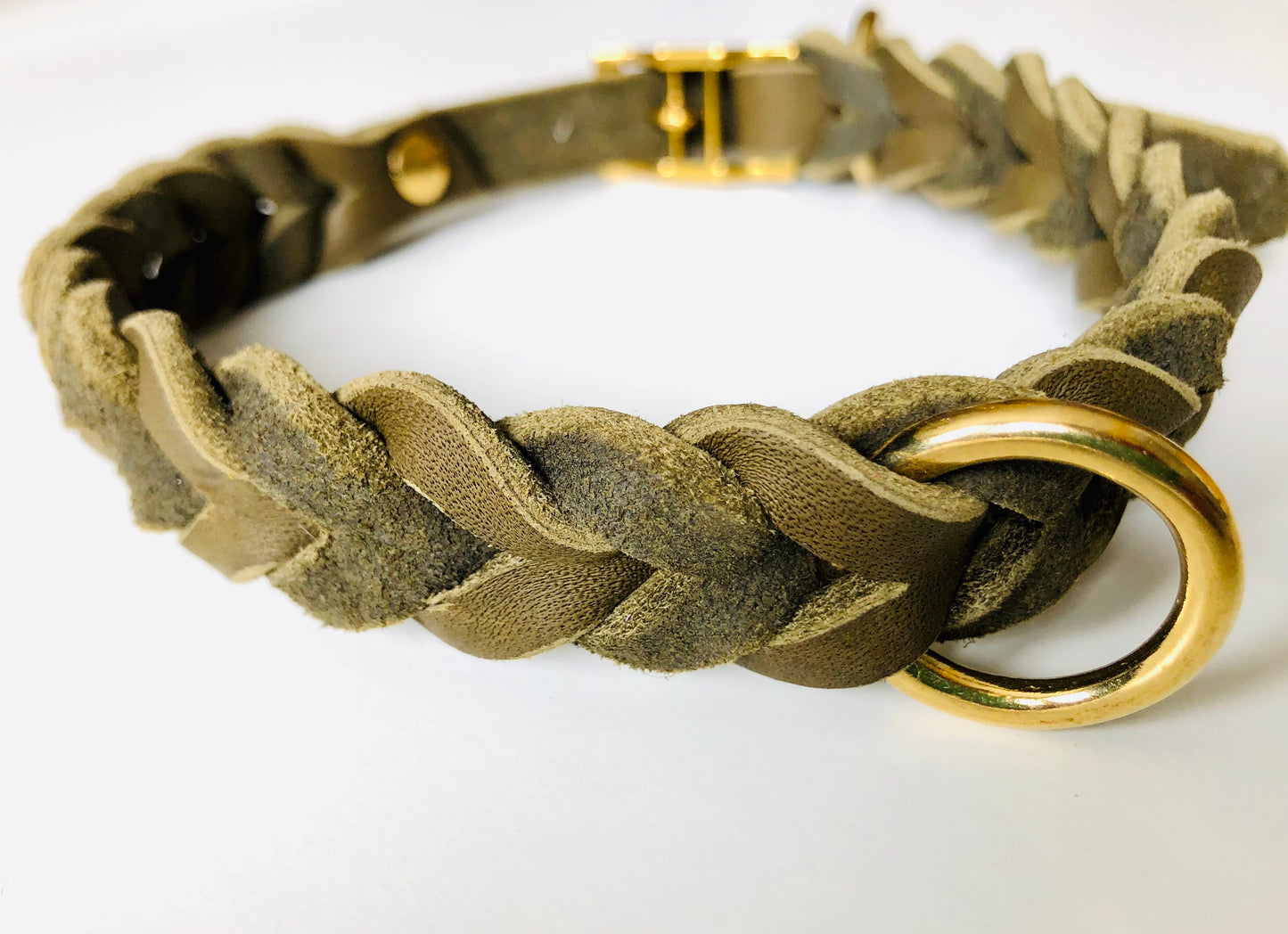 Nahaufnahme eines Halsbandes in Olive aus Leder geflochten mit goldenen Beschlägen