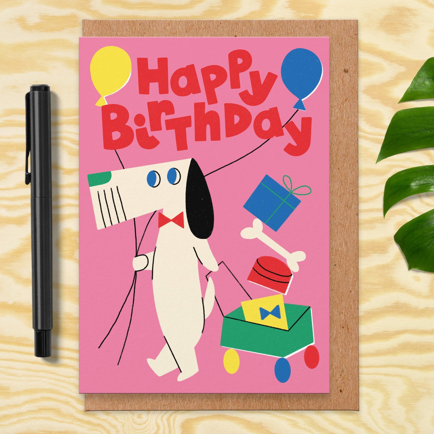 Geburtstagskarte mit Umschlag. Auf der Vordeite ist ein gezeichneter Hund zu sehen, der Ballons und Geschenke hat mit der Aufschrift Happy Birthday"