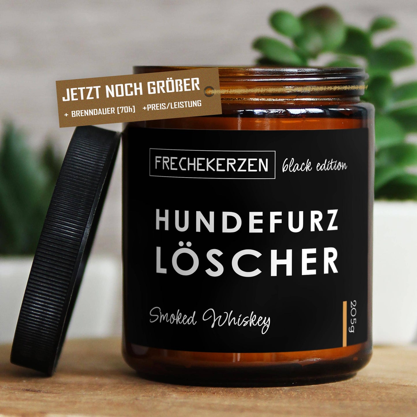 Dunkelbraunes Glas mit schwarzem Deckel, der danbene liegt. Die Aufschrift sagt Hundefurzlöscher, es ist ein eDuftkerze mit dem Aroma Smoked Whiskey.